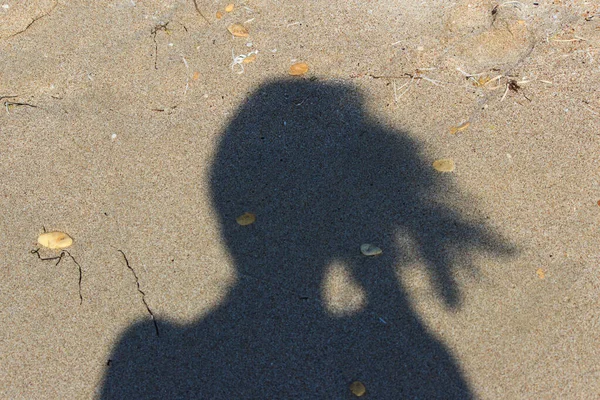 Sombra de una chica en el fondo de la ola de mar que se aproxima. Playa arenosa — Foto de Stock