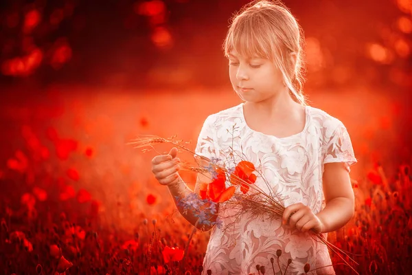 特写在罂粟地里的一个可爱的女孩在露天的花朵 在罂粟的女孩 金发碧眼的小女孩和一束鲜花站在罂粟地里的白色上衣 — 图库照片
