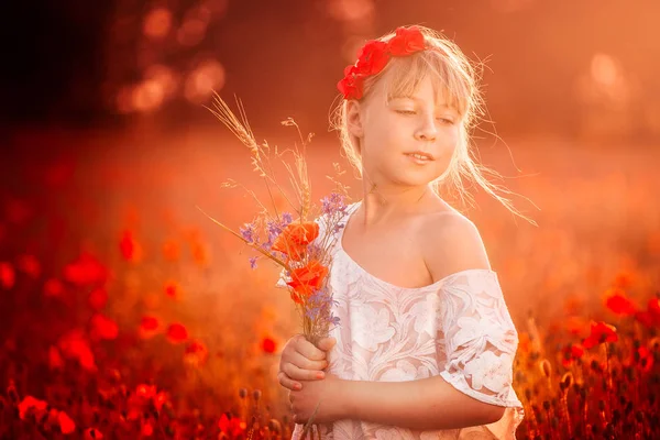 特写在罂粟地里的一个可爱的女孩在露天的花朵 在罂粟的女孩 金发碧眼的小女孩和一束鲜花站在罂粟地里的白色上衣 — 图库照片