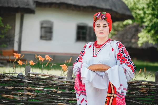 Egy Ukrán Hagyományos Öltözékben Tartja Rushnyk Kenyér Háttérben Ház Flowers — Stock Fotó