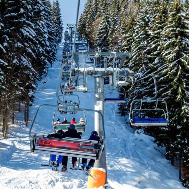 Kayakçı ve Snowboard düşkünleri teleferik kış orman arasında üzerinde yukarıdan bir kayak lift.view üzerinde. Teleferik ve Kayak pistlerindeki Bukovel içinde.