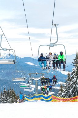 Kayakçı ve Snowboard düşkünleri teleferik kış orman arasında üzerinde yukarıdan bir kayak lift.view üzerinde. Teleferik ve Kayak pistlerindeki Bukovel içinde.