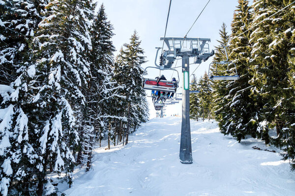 Skiers and snowboarders on a ski lift.view from above on the cable car among the winter forest. The cable car and ski slopes in Bukovel.