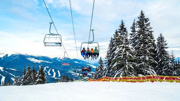 Kayakçı ve Snowboard düşkünleri teleferik kış orman arasında üzerinde yukarıdan bir kayak lift.view üzerinde. Teleferik ve Kayak pistlerindeki Bukovel içinde.