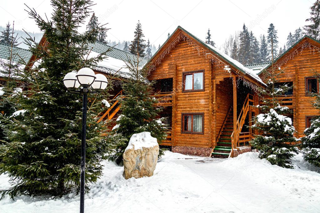 Wooden cottage house in mountain resort. Christmas winter landscape. Beautiful winter cottage covered snow
