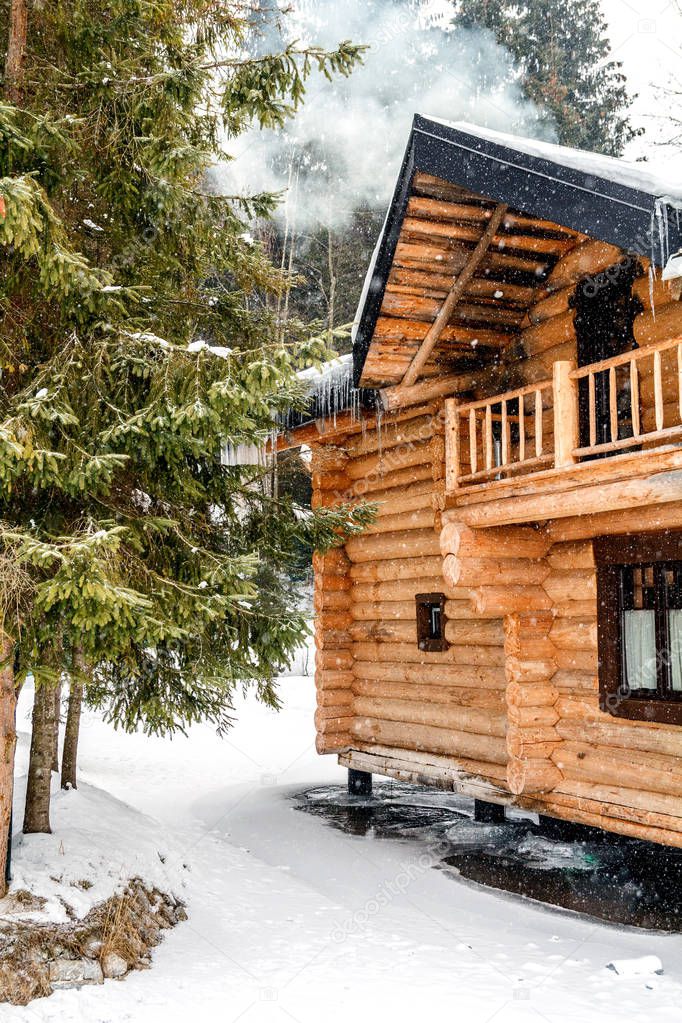 Wooden cottage house in mountain resort. Christmas winter landscape. Beautiful winter cottage covered snow