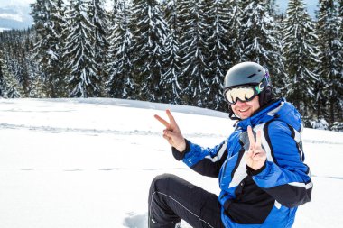 Bir dağın tepesinde kar kış spor giyim seyir uzakta, giyen büyük yansıtılmış Kayak mask.a adam mavi Kayak takım elbiseli Genç yakışıklı adam oturuyor