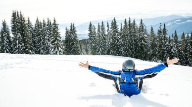 Bir dağın tepesinde kar kış spor giyim seyir uzakta, giyen büyük yansıtılmış Kayak mask.a adam mavi Kayak takım elbiseli Genç yakışıklı adam oturuyor
