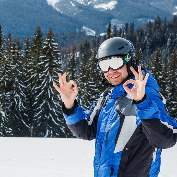 年轻英俊的男子在冬季运动服看着 戴着大镜子滑雪面具 穿蓝色滑雪服的男子看着相机和微笑 — 图库照片