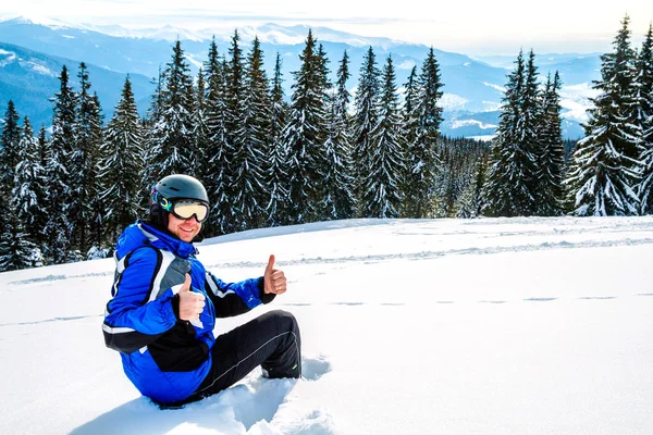 Bir dağın tepesinde kar kış spor giyim seyir uzakta, giyen büyük yansıtılmış Kayak mask.a adam mavi Kayak takım elbiseli Genç yakışıklı adam oturuyor
