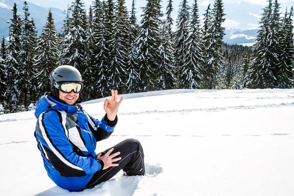 Bir dağın tepesinde kar kış spor giyim seyir uzakta, giyen büyük yansıtılmış Kayak mask.a adam mavi Kayak takım elbiseli Genç yakışıklı adam oturuyor