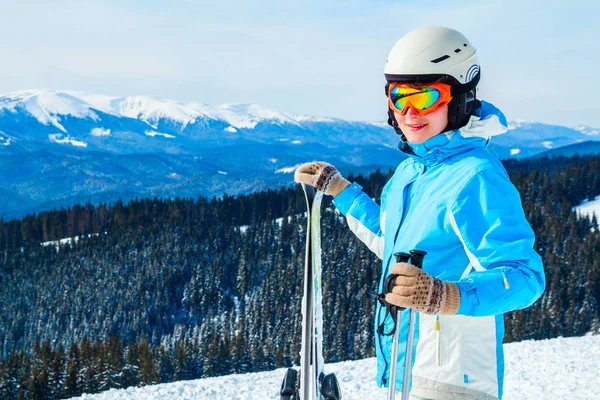 穿着蓝色西装的女人 头盔和眼镜站在山顶上的滑雪板上 — 图库照片