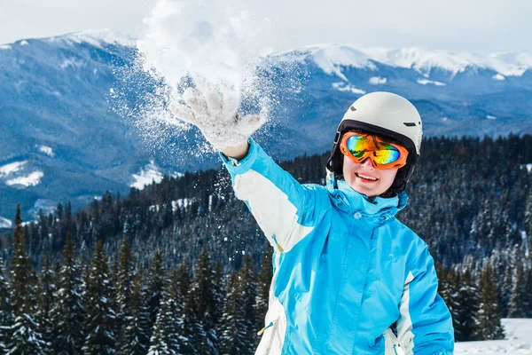 一个穿着蓝色滑雪服和面具的妇女在山顶上的相机上投掷雪 女孩在镜头前扔雪 — 图库照片