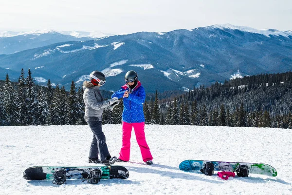 iki kadın kayak dağ selfie üstüne uygun. Kızlar snowboard ile kar üzerinde oturmak ve fotoğraflandı.