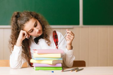 okul üniforması masasında kitap ve kalem ile yeşil ışık yanmadı arka plan üzerinde oturan kız öğrenci.