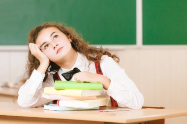 kız öğrenciler okul üniformalı çiftler sınıfta oturmak. Kızlar okula gidiyorum. Kız öğrenciler sınıfta kitap okumak ve bir akıllı telefon kullanma