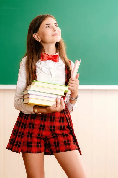 美しい若い中の女学生学校制服立っている彼女の手の本と — ストック写真