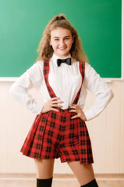 美丽的年轻女学生在学校制服站在学校董事会的背景 — 图库照片