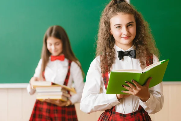 Zwei Lustige Schulmädchen Schuluniform Stehen Mit Büchern Auf Dem Hintergrund — Stockfoto