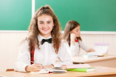 kız öğrenciler okul üniformalı çiftler sınıfta oturmak. Kızlar okula gidiyorum. Kız öğrenciler sınıfta kitap okumak ve bir akıllı telefon kullanma