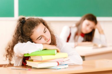 kız öğrenciler okul üniformalı çiftler sınıfta oturmak. Kızlar okula gidiyorum. Kız öğrenciler sınıfta kitap okumak ve bir akıllı telefon kullanma