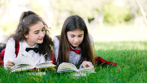 面白い女子中学生が草の上に横たわると読書 女の子 ガール フレンド 姉妹が自然の中の教訓を教えています — ストック写真
