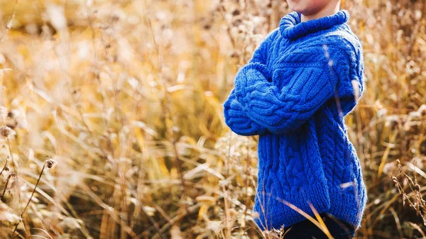 一个穿着蓝色保暖针织毛衣的男孩在田野里交叉双臂 — 图库照片
