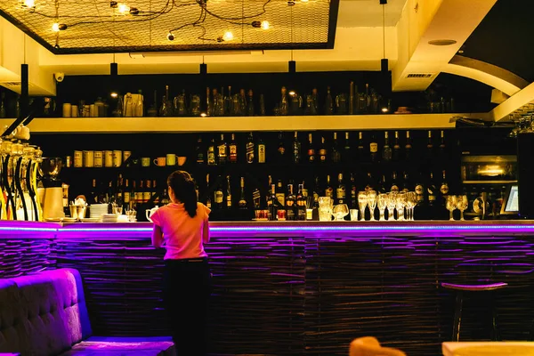 ışıklı bir bar içecekler ve ters duran bir garson kız olan sayaç.