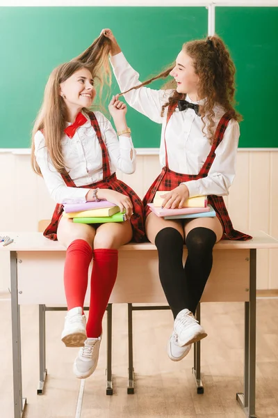 Дві Брюнетки Школярки Сидять Класі Столом Книгами Фоні Дошки Отримують — стокове фото
