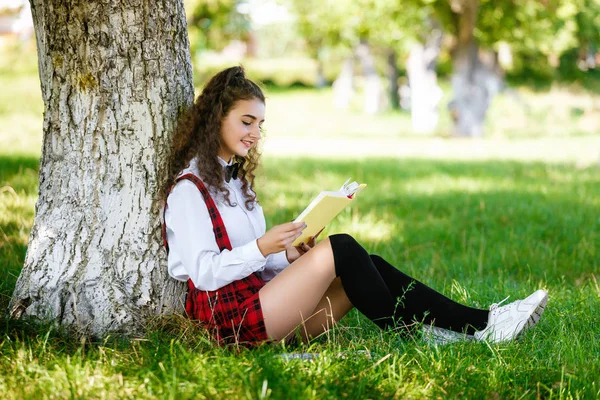 Mooie Schoolmeisje Een Geblokte Rode School Uniform Zit Een Park — Stockfoto