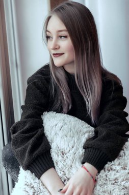 Penceredeki tek başına oturan ve pencereden dışarı bakarak güzel genç kız.