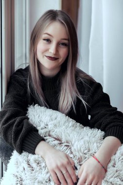 pencere üzerinde yalnız oturan ve kamera bakıyor ve gülümseyen güzel genç kız.