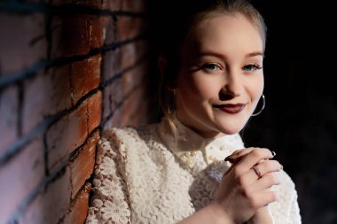 Genç güzel kadın tuğla duvara duruyor. Portre duvushki yakın çekim, hangi bir tuğla duvara dayanır