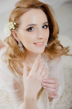 Parlak bir odada sarı saçlı güzel kız yerde yatıyor. Gelin kameraya bakarak yalan ve gülümseyerek