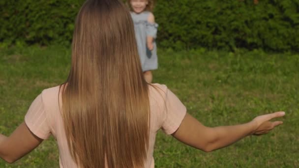 慢动作宝宝冲进母亲的怀里 在公园的夏日灯光下微笑 宝宝笑了绿草背景 快乐的家庭理念 宝宝玩得开心点长的头发的妇女 — 图库视频影像