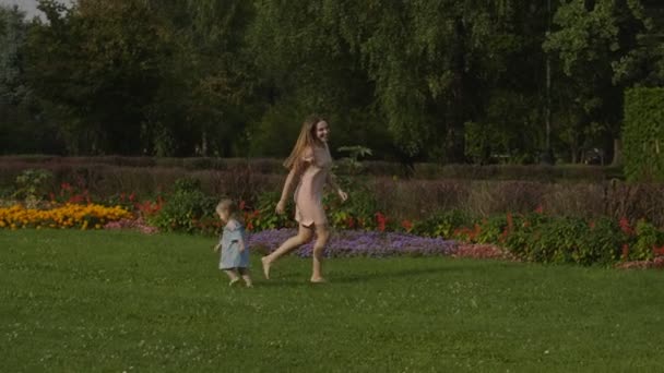 Niña Con Madre Jugando Con Bola Roja Sobre Hierba Verde — Vídeos de Stock