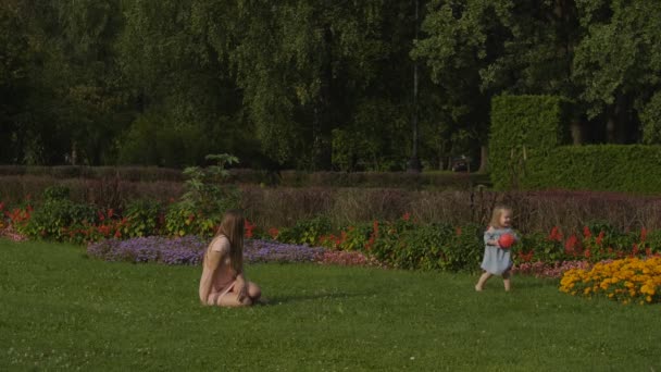 Baby Flicka Med Mamma Leker Med Röd Boll Grönt Gräs — Stockvideo