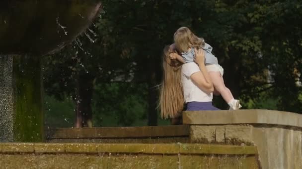 Menina Com Mãe Sentada Perto Fonte Rir Abraçar Luz Pôr — Vídeo de Stock