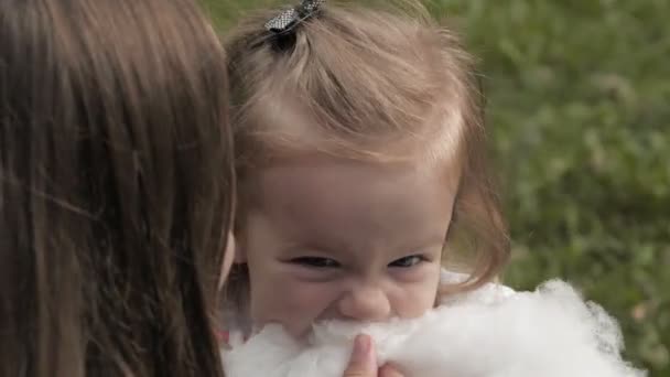 在公园里和妈妈一起玩的开心和分享棉花糖 微笑的婴孩的画像吃棉花糖并且看照相机 — 图库视频影像