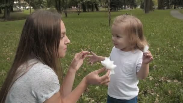 在公园里和妈妈一起玩的开心和分享棉花糖 微笑的婴孩的画像吃棉花糖并且看照相机 — 图库视频影像