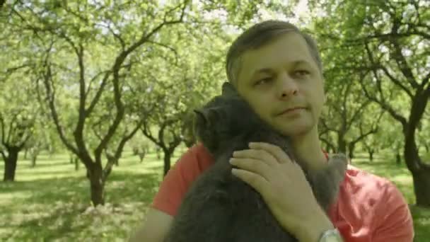 Mutlu Gülümseyen Gülen Yakışıklı Adam Bir Kedi Okşayarak Yeşil Ağaçlar — Stok video
