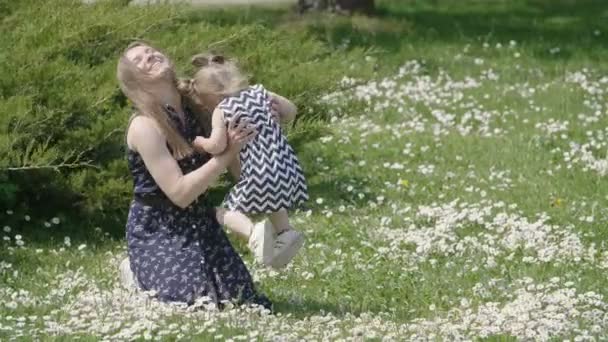 Liten Flicka Med Mamma Liggande Grönt Gräs Med Vita Blommor — Stockvideo