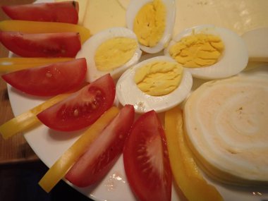 bir kahvaltı tabağı üzerinde yumurta ve sebze ile peynir