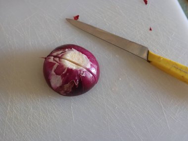 Mutfaktaki beyaz kesme tahtasındaki kırmızı soğan.