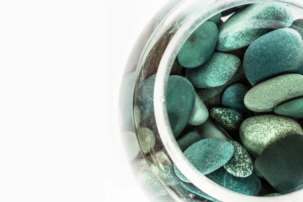 Zee stenen turquoise in een glazen vaas vol water op een witte achtergrond Rechtenvrije Stockfoto's