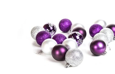 Beyaz arka planda menekşe ve gümüş noel toplarının olduğu noel kartı.