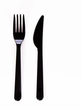 Beyaz arka planda siyah plastik çatal ve bıçak var..