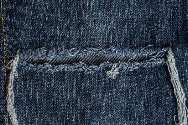 Zerrissene alte blaue Jeans mit gelben Nähten Hintergrund — Stockfoto