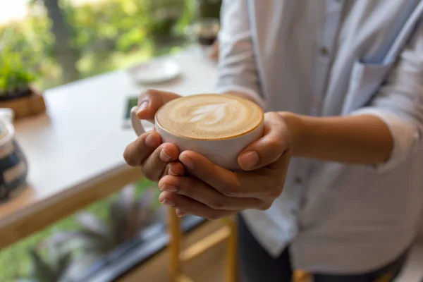 Mulher mão segurando xícara de café no café — Fotografia de Stock