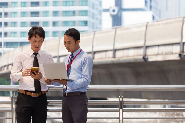 Dos hombres de negocios están trabajando codo a codo con un teléfono inteligente y sin él. Imágenes de stock libres de derechos